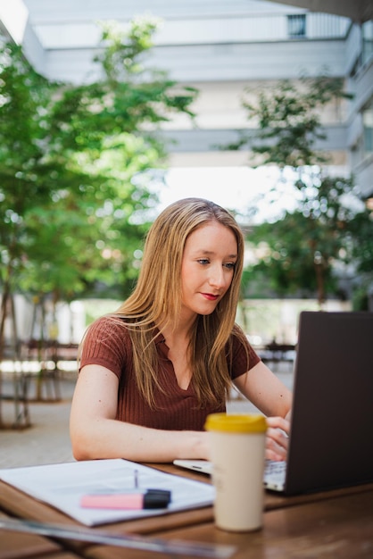 Aufnahme einer jungen Studentin, die Hausaufgaben macht, während sie auf ihrem Computer auf dem Campus tippt