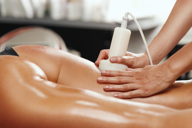 Aufnahme einer nicht erkennbaren Frau, die im Schönheitssalon eine Anti-Cellulite-Massage bekommt. Sie hat eine Ultraschallkavitationsbehandlung zur Fettreduktion.