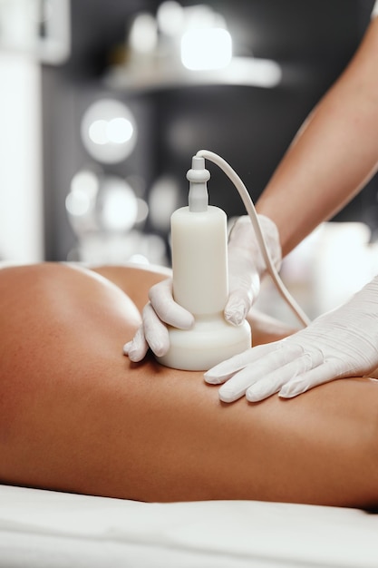 Aufnahme einer nicht erkennbaren Frau, die im Schönheitssalon eine Anti-Cellulite-Massage bekommt. Sie hat eine Ultraschallkavitationsbehandlung zur Fettreduktion.