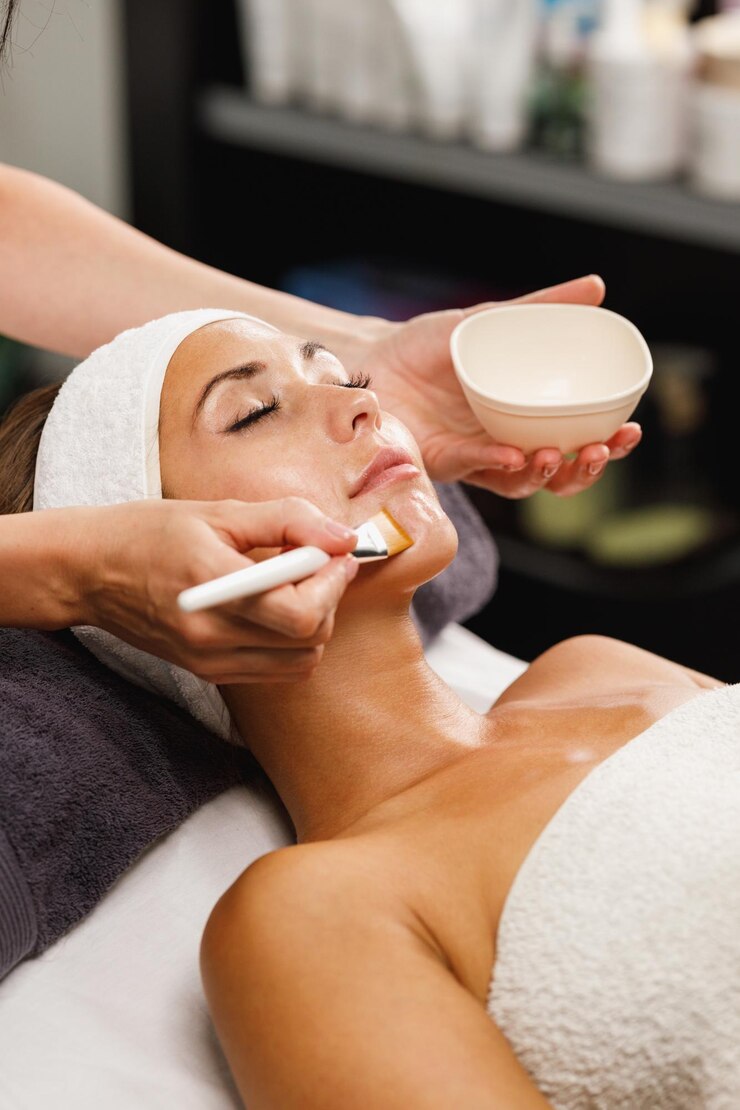 Foto aufnahme einer schönen jungen frau, die im schönheitssalon eine gesichtsmaskenbehandlung erhält.