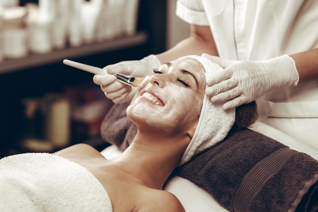 Aufnahme einer schönen jungen Frau, die im Schönheitssalon eine Gesichtsmaskenbehandlung erhält.