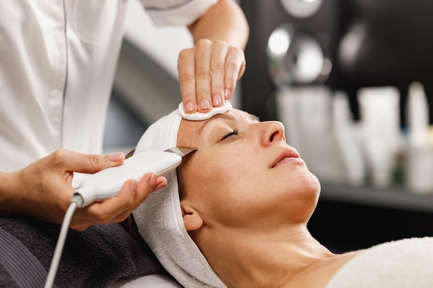 Aufnahme einer schönen reifen Frau bei einer Ultraschall-Gesichtsbehandlung im Schönheitssalon.