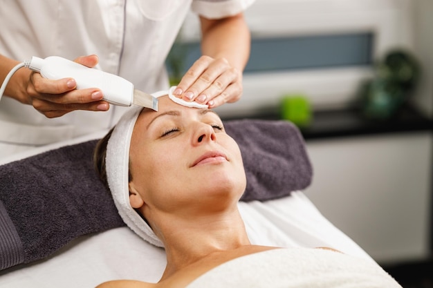 Aufnahme einer schönen reifen Frau bei einer Ultraschall-Gesichtsbehandlung im Schönheitssalon.