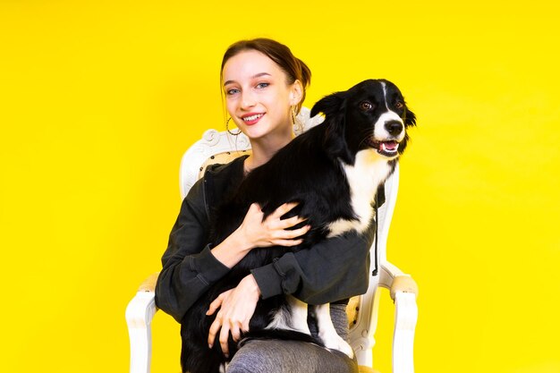 Aufnahme einer Sportlerin in Leggings mit einem Border-Collie-Hund isoliert auf gelbem und rotem Hintergrund