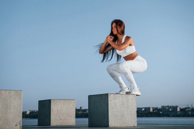 Aufnahme einer sportlichen Frau, die tagsüber Fitnessübungen in der Nähe des Sees macht?