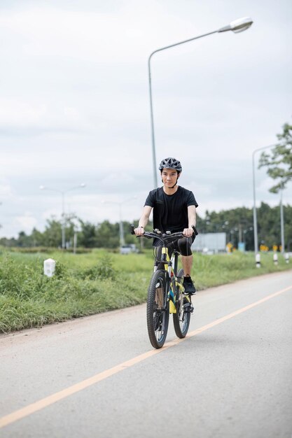 Aufnahme eines glücklichen asiatischen Typen, der im Sommerpark Radfahren genießt Sport, Freizeit und gesundes Lebensstil Konzept