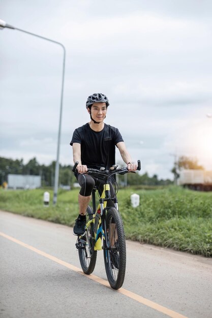 Aufnahme eines glücklichen asiatischen Typen, der im Sommerpark Radfahren genießt Sport, Freizeit und gesundes Lebensstil Konzept