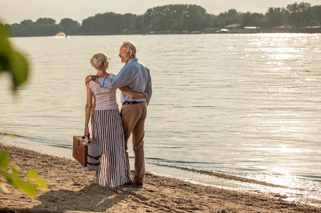 Aufnahme eines glücklichen Seniorenpaares, das am Flussufer picknickt
