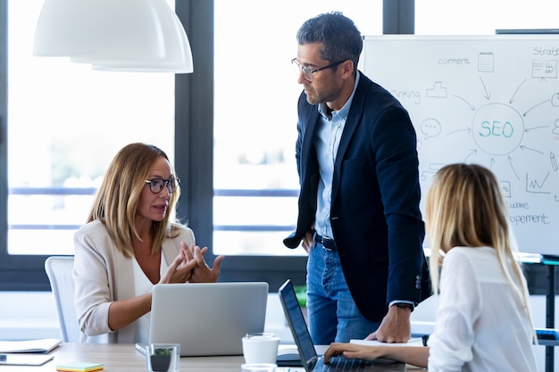 Aufnahme eines gutaussehenden Geschäftsmannes, der mit Kollegen in der Besprechung im Coworking Space spricht.