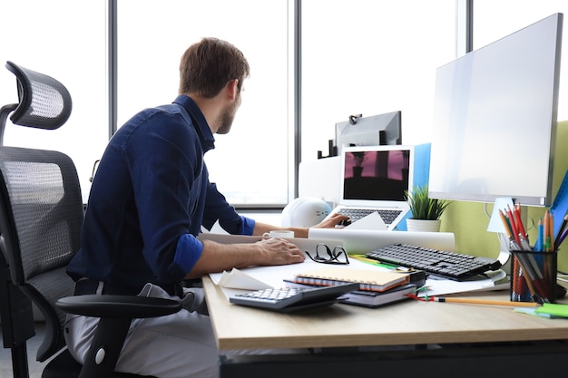 Aufnahme eines gutaussehenden männlichen Architekten, der in seinem Büro an einem Design arbeitet.