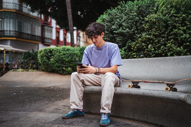 Aufnahme eines jungen Skater-Mannes, der sich auf sein Telefon konzentriert. Er sendet eine Textnachricht an seinen Freund