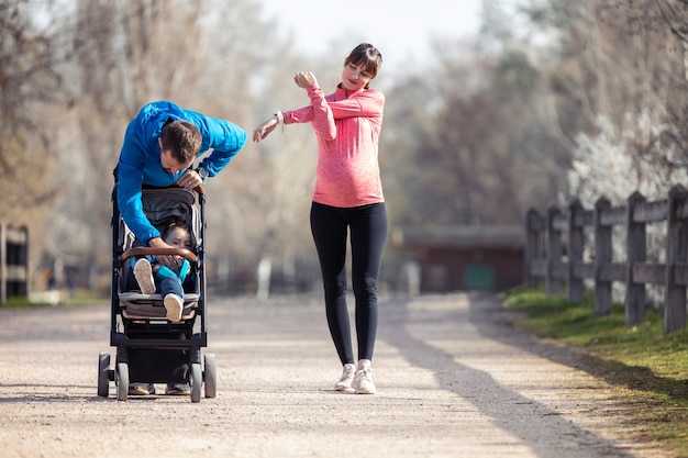 Aufnahme eines sportlichen jungen Paares mit ihrem kleinen Sohn, der sich beim Gehen streckt und die gemeinsame Zeit im Freien genießt.