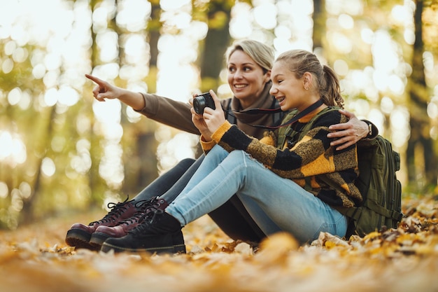 Aufnahme eines Teenager-Mädchens und ihrer Mutter, die im Herbst gemeinsam durch den Wald gehen.