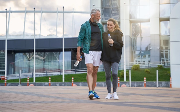 Aufnahme in voller Länge von einem aktiven Paar mittleren Alters in Sportkleidung, das beim gemeinsamen Gehen fröhlich aussieht