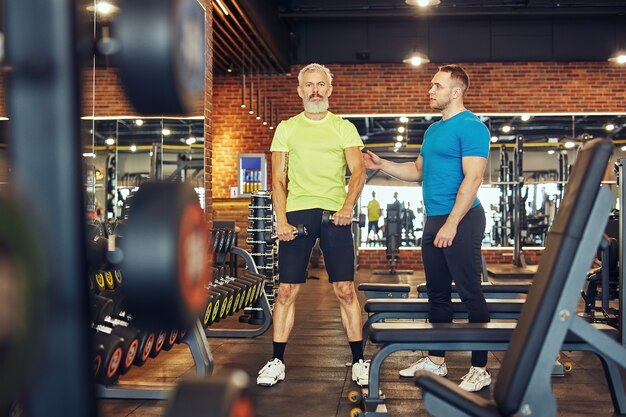 Aufnahme in voller Länge von einem reifen kaukasischen Mann in Sportbekleidung, der mit Hanteln unter trainiert