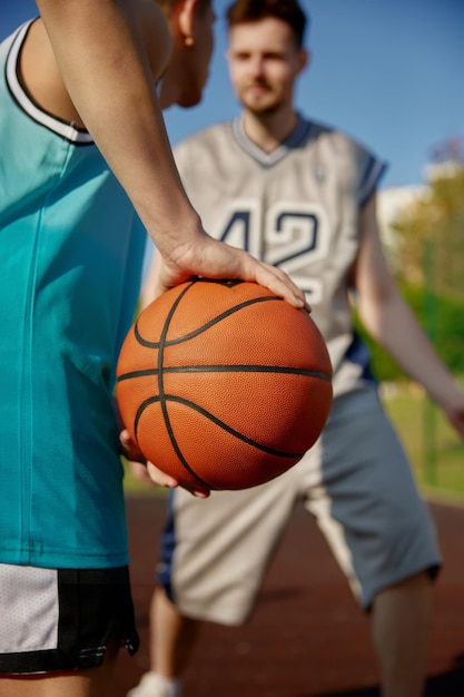 Aufnahme von zwei Männern, die Basketball spielen. Fokus auf den Ball in der Hand, der sich auf den Pass vorbereitet. Aktive Zeit