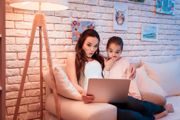 Aufpassende Filme der Mutter und der Tochter auf Laptop.