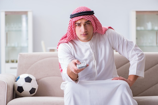 Aufpassender Sportfußball des arabischen Mannes am Fernsehen