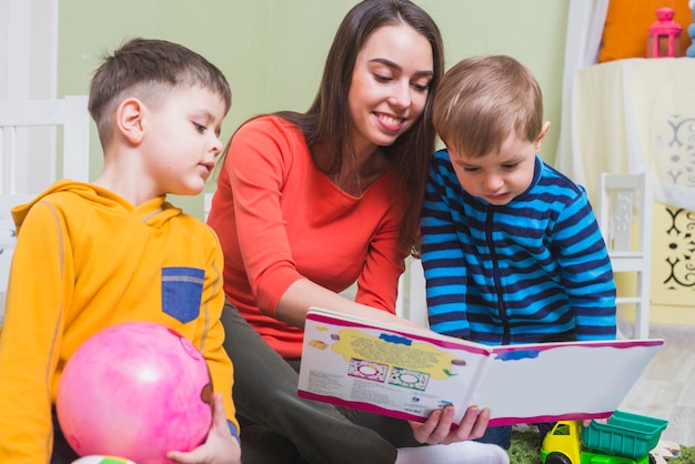 Aufpassendes Buch der Frau mit Jungen