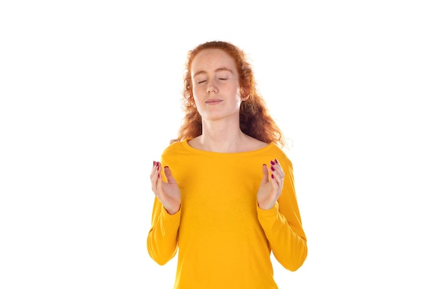 Aufrichtige rothaarige Frau hält die Hände zusammen und betet in Pose
