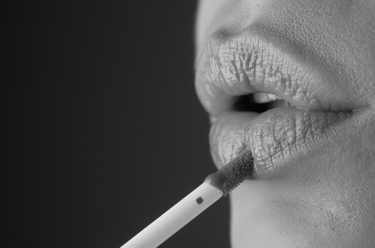 Foto auftragen von lippenstift. lippen mit hellem lippenstift in nahaufnahme bemalen. verwöhnendes lippenkorrekturkonzept. glänzender lippenstift auf voller, praller lippe. frau trägt lippenstift mit der hand auf