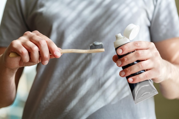 Auftragen von Zahnpasta auf eine Bambuszahnbürste Hände drücken Tube mit Zahnpasta aus Zahnheilkunde und Hygienekonzept