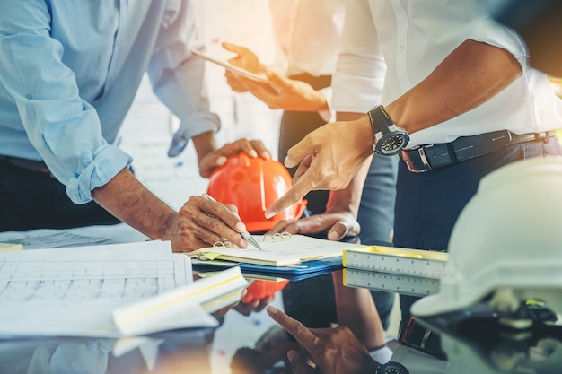 Auftragnehmer und Ingenieur mit Plänen besprechen sich an einer modernen Baustelle, Ingenieure in den mechanischen Fabrikleseanweisungen