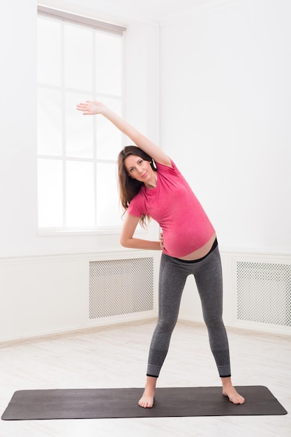 Aufwärmtraining der schwangeren Frau zu Hause. Werdende Frau macht Aerobic-Übungen, gesundes Schwangerschaftskonzept