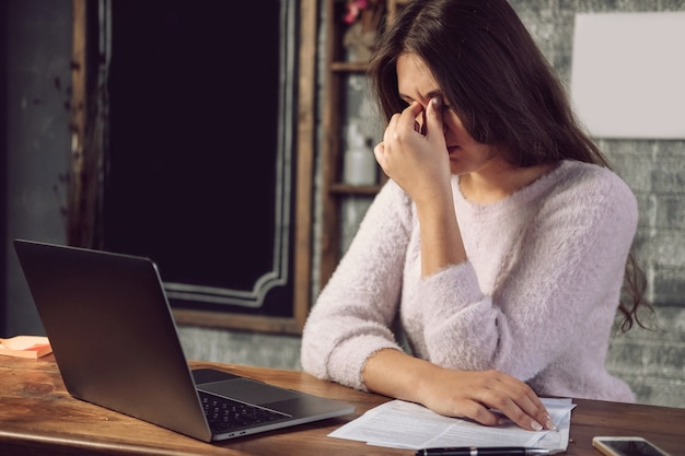 Augenschmerzen beim Arbeiten am Laptop, reibt sich die Augen