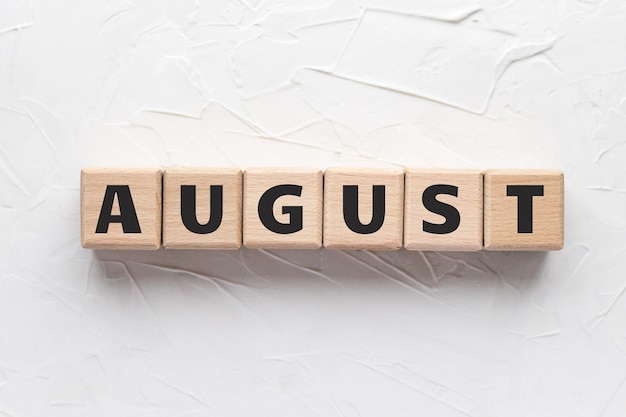 August-Text auf Holzwürfeln auf weißem strukturiertem Hintergrund