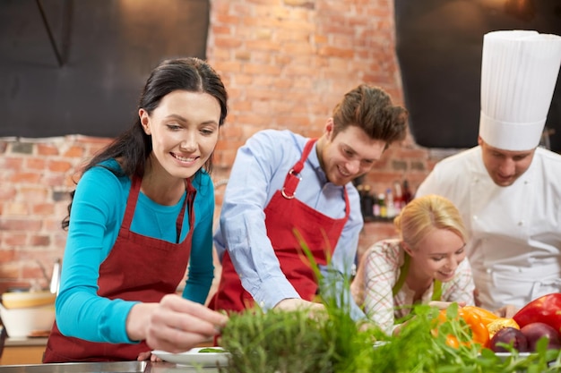 aula de culinária, culinária, comida e conceito de pessoas - casal feliz e chef masculino cozinham e decoram pratos na cozinha