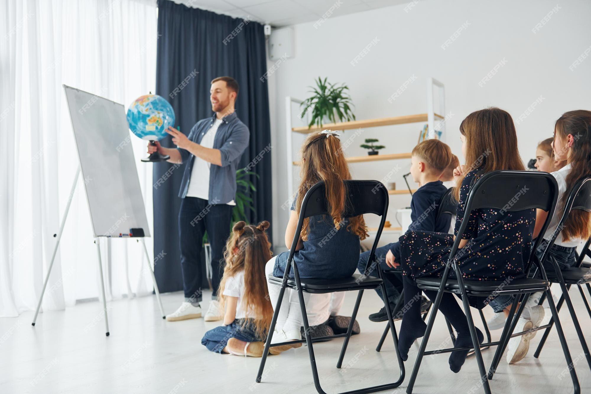 Aula de geografia com globo nas mãos grupo de alunos de crianças