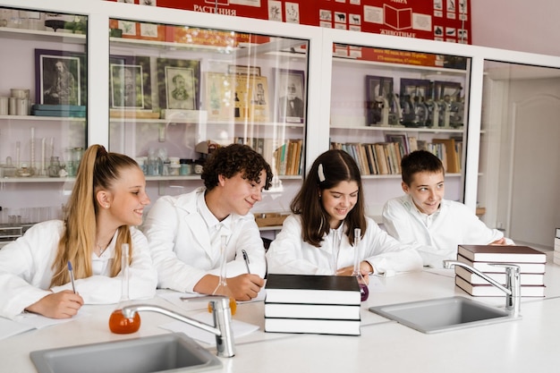 Aula de química em laboratório na escola Alunos escrevendo lição de casa sorrindo e se divertindo juntos no laboratório da escola