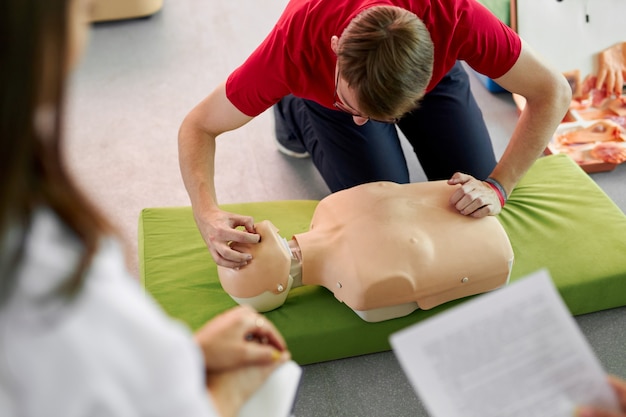 Aula de RCP com um jovem instrutor demonstrando ajuda nos primeiros socorros