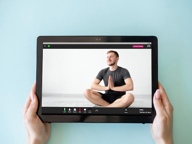 Aula de vídeo de ioga Meditação online Treinamento virtual Mãos de mulher segurando tablet com homem relaxado em pose de lótus na tela isolada em azul