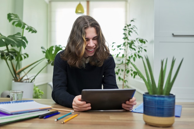 Aula on-line cara estudante adolescente estudando em casa remotamente usando tablet digital