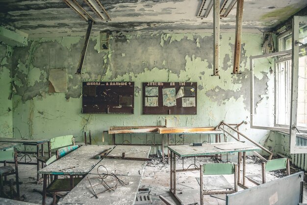 Foto aula en ruinas con escritorios y pizarras en la escuela de pripyat