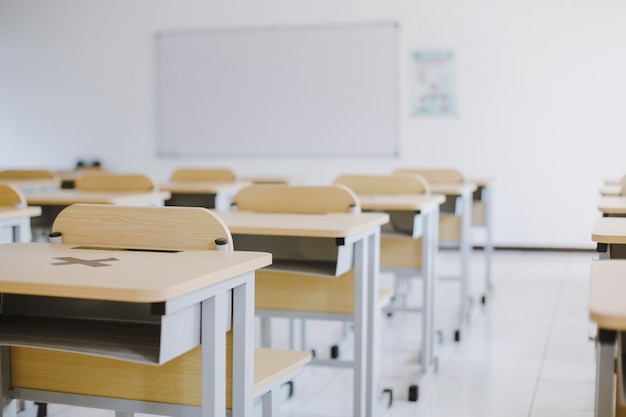 Aula vacía sin estudiantes con escritorios, sillas y pizarra durante la pandemia