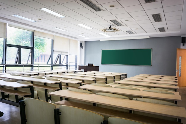 Aula vacía con sillas, escritorios y pizarra.