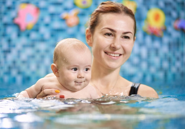 Aulas de natação para bebês com mãe na piscina durante o treinamento