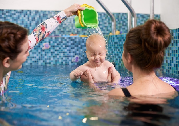 Foto aulas de natação para bebês com mãe na piscina durante o treinamento