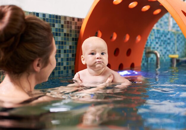 Foto aulas de natação para os mais pequenos, bebé com a mãe na piscina durante o treino