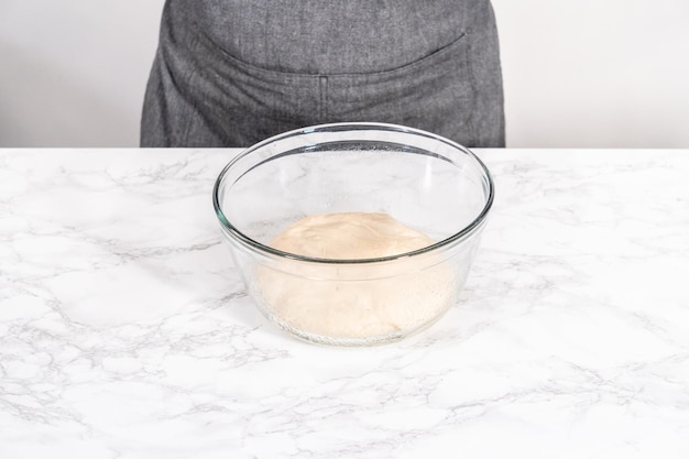 Foto aumento de masa de pizza en un recipiente de vidrio para preparar pizza de postre de canela