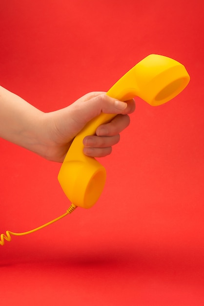 Auricular amarillo sobre un rojo en la mano de la mujer.