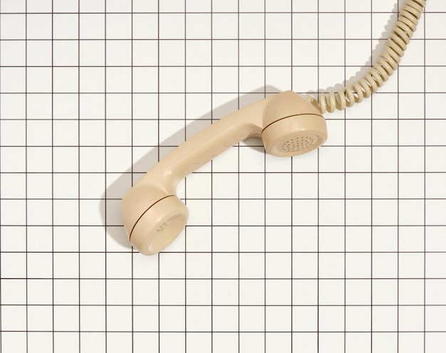 Un auricular de teléfono beige se encuentra sobre la mesa Espacio de copia plano para texto Estilo de moda retro vintage