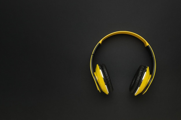 Auriculares amarillos brillantes sobre un fondo negro El concepto de accesorios musicales con estilo Flat lay