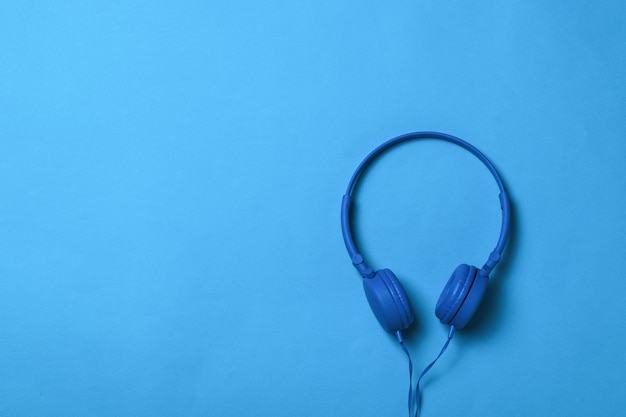 Auriculares azules con un cable azul sobre una superficie azul