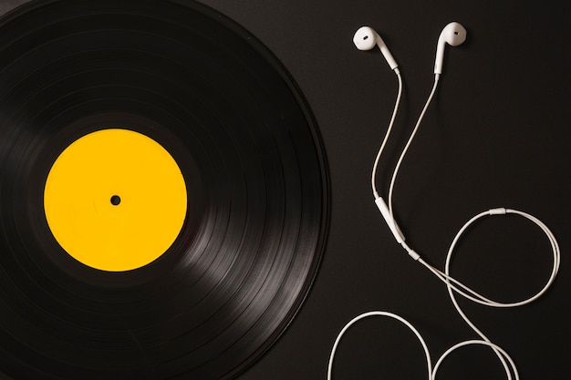 Foto auriculares blancos y disco de vinilo sobre fondo negro