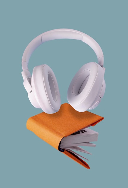 Auriculares blancos y un libro naranja volando sobre un fondo azul cerrado