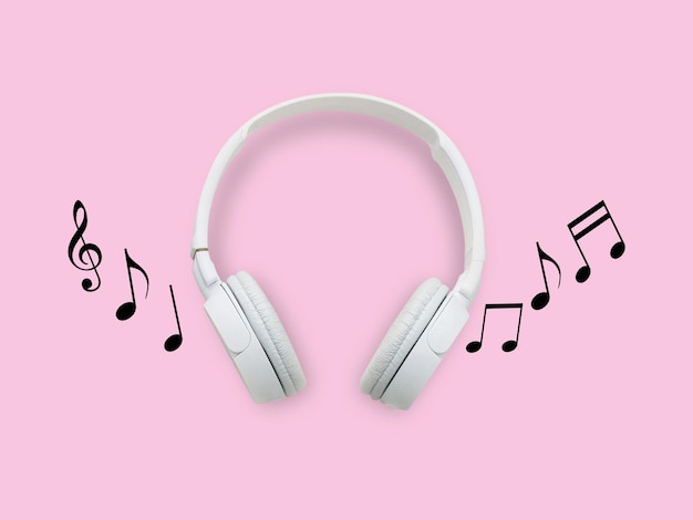 Foto auriculares blancos y notas musicales sobre fondo rosa.